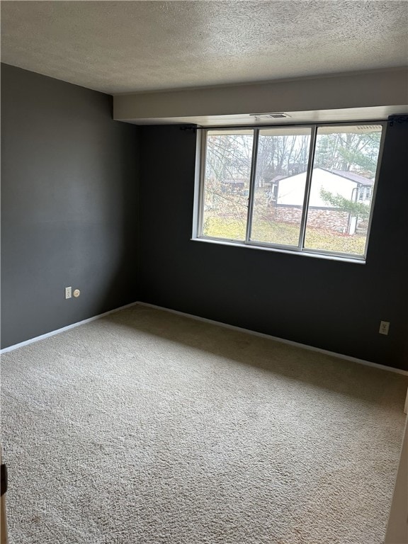 unfurnished room featuring carpet, a textured ceiling, and baseboards