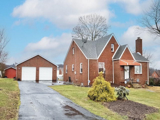 view of front of house featuring an outdoor structure, brick siding, a detached garage, and a front lawn