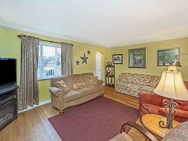 living area featuring arched walkways, crown molding, and light wood finished floors