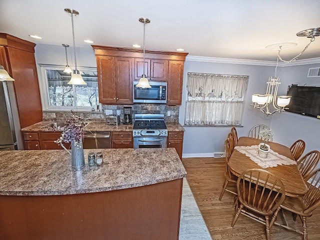 kitchen featuring tasteful backsplash, light wood-style flooring, ornamental molding, stainless steel appliances, and pendant lighting