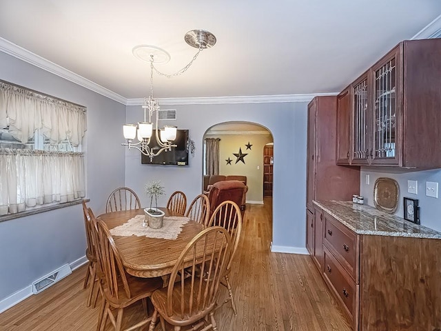 dining space featuring arched walkways, crown molding, visible vents, wood finished floors, and baseboards