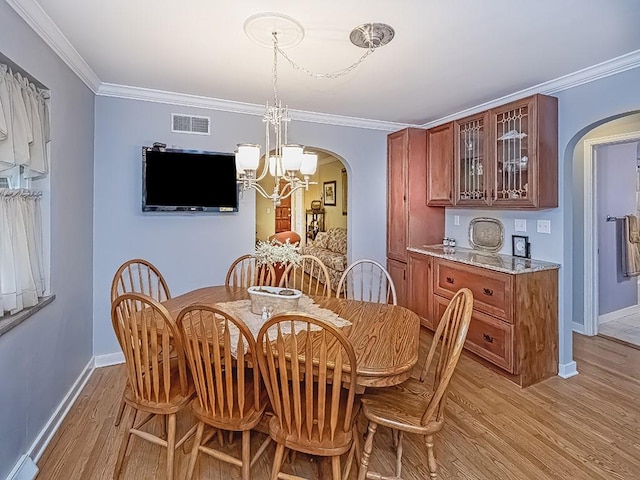 dining room with ornamental molding, arched walkways, visible vents, and light wood-style flooring