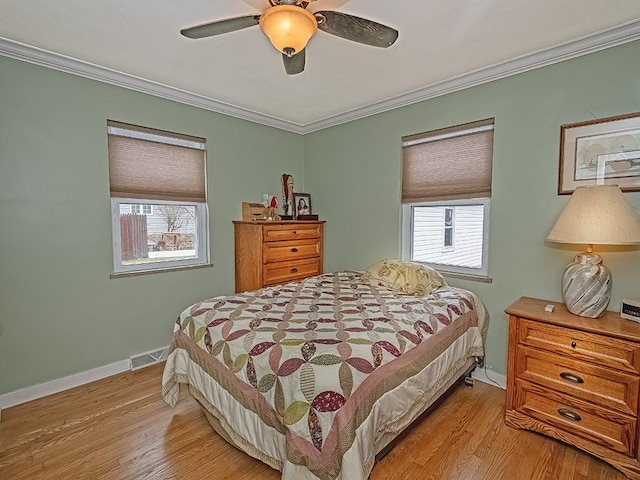 bedroom with baseboards, light wood-style flooring, visible vents, and crown molding