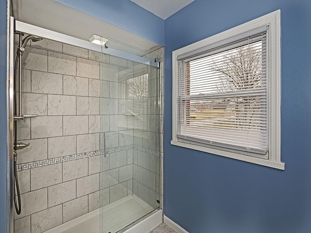 bathroom featuring tiled shower and baseboards