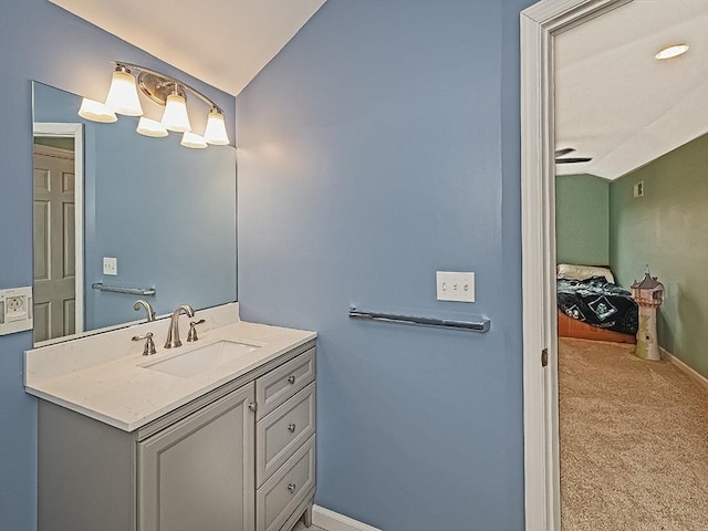 bathroom featuring baseboards, vaulted ceiling, and vanity