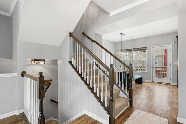 stairway featuring a notable chandelier, baseboards, and wood finished floors