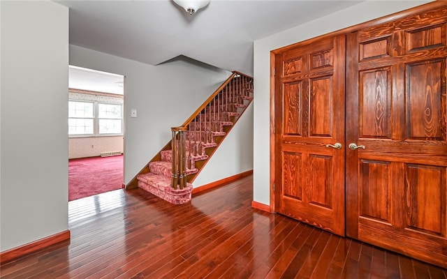 stairs with a baseboard heating unit, wood-type flooring, and baseboards