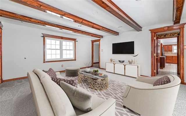 living area with beam ceiling, light carpet, and baseboards