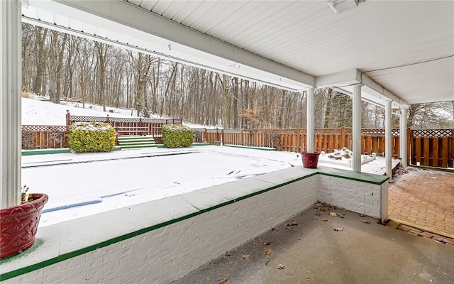 snow covered patio with a fenced backyard