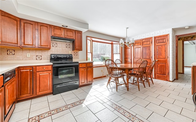 kitchen with decorative backsplash, decorative light fixtures, black / electric stove, light countertops, and under cabinet range hood