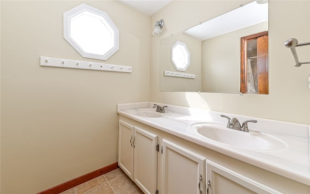 full bath featuring double vanity, baseboards, a sink, and tile patterned floors