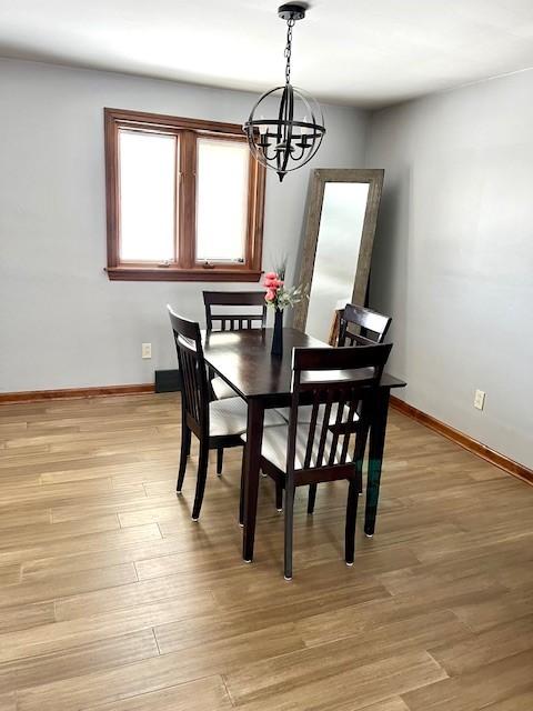 dining space with light wood-style flooring, baseboards, and a chandelier