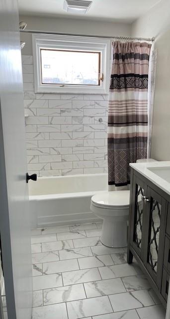 full bath featuring marble finish floor, shower / tub combo with curtain, visible vents, toilet, and vanity