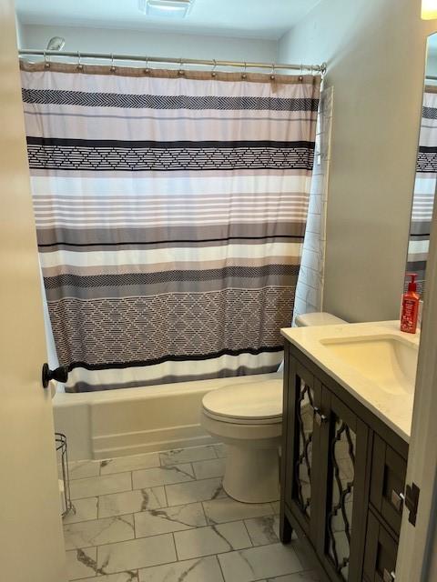 bathroom featuring toilet, marble finish floor, shower / bath combo, and vanity