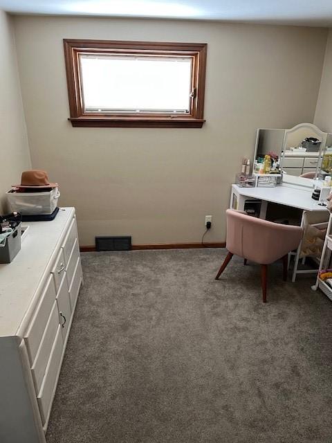 office space with dark colored carpet, visible vents, and baseboards