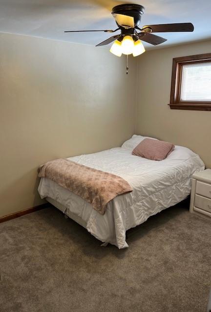 bedroom with dark colored carpet, a ceiling fan, and baseboards