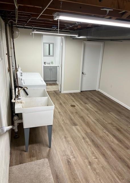 unfinished basement with washer and clothes dryer, light wood-style flooring, and baseboards