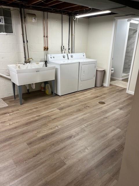 laundry room with washing machine and dryer, laundry area, a sink, and light wood-style flooring