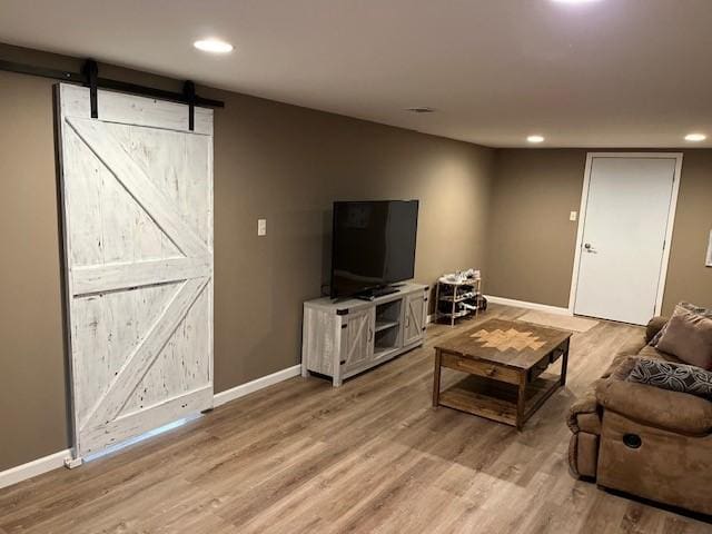 living area with recessed lighting, light wood-style flooring, baseboards, and a barn door