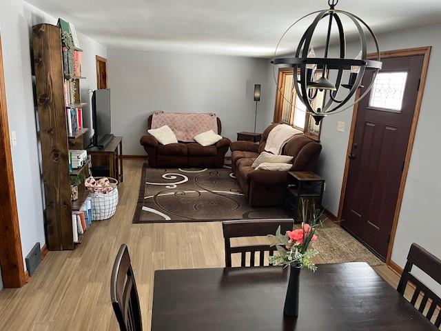 dining room featuring light wood-style floors, a chandelier, and baseboards