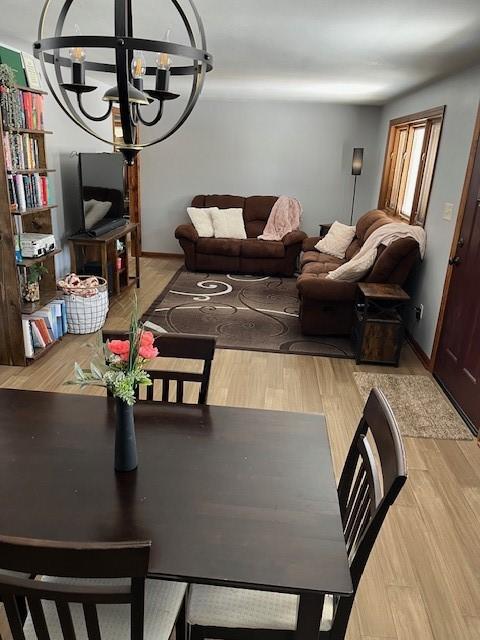 dining room with baseboards, light wood-type flooring, and a notable chandelier