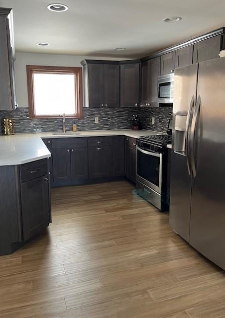 kitchen featuring appliances with stainless steel finishes, light wood-style floors, light countertops, and a sink