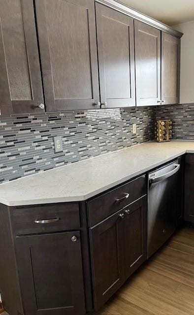 kitchen featuring stainless steel dishwasher, light wood-type flooring, dark brown cabinetry, and decorative backsplash