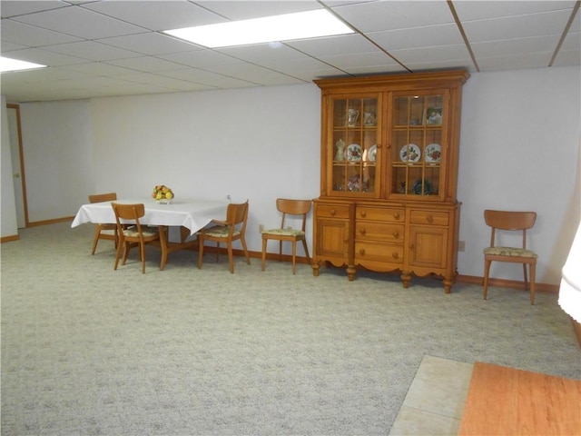dining room featuring light colored carpet, a drop ceiling, and baseboards