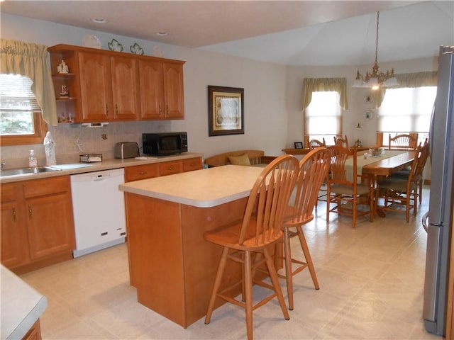 kitchen featuring a center island, light floors, light countertops, white dishwasher, and black microwave