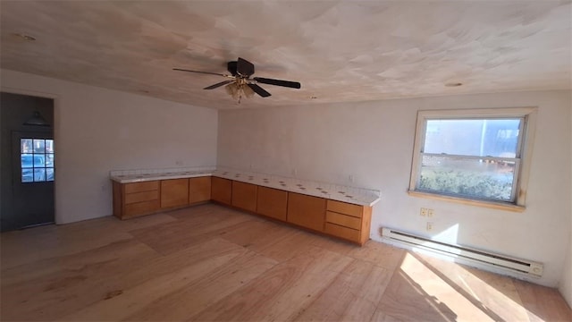 kitchen featuring a baseboard radiator, light countertops, light wood-style floors, a ceiling fan, and light brown cabinets