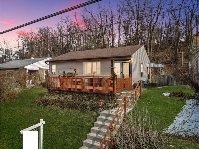 view of front of home with roof with shingles, a lawn, and a wooden deck