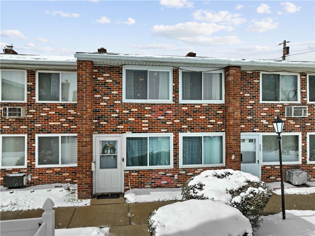 townhome / multi-family property featuring an AC wall unit and brick siding