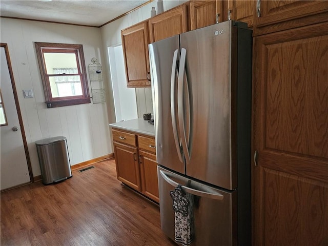 kitchen with brown cabinets, wood finished floors, light countertops, and freestanding refrigerator