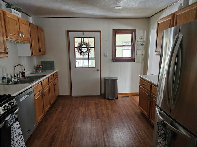 kitchen featuring appliances with stainless steel finishes, brown cabinets, light countertops, and a sink