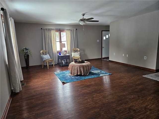 living area with baseboards, visible vents, ceiling fan, and dark wood-type flooring