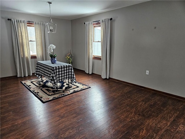 unfurnished dining area featuring a chandelier, baseboards, and wood finished floors