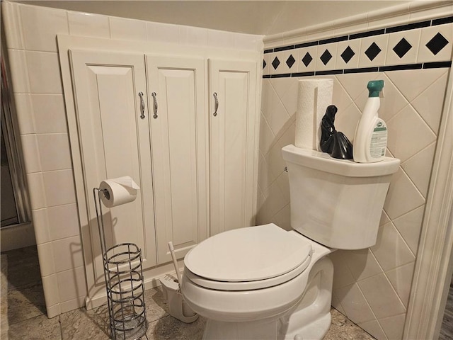 half bath with toilet and tile walls