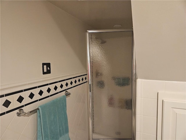 full bath featuring wainscoting, a shower stall, and tile walls