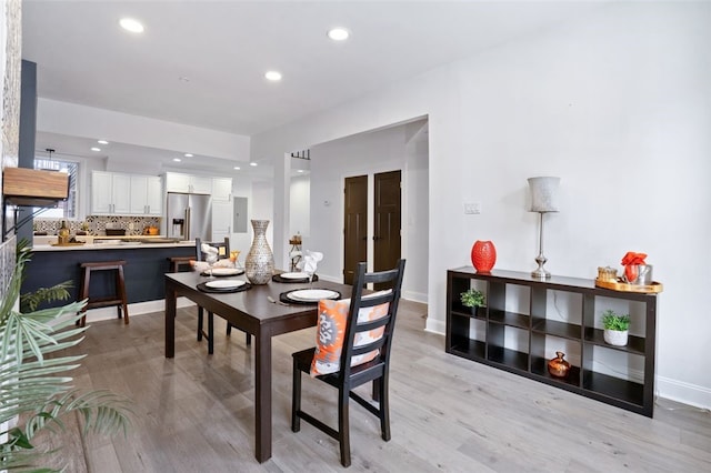 dining area featuring baseboards, light wood finished floors, and recessed lighting