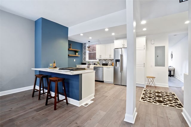 kitchen featuring light countertops, appliances with stainless steel finishes, white cabinets, a peninsula, and a kitchen breakfast bar