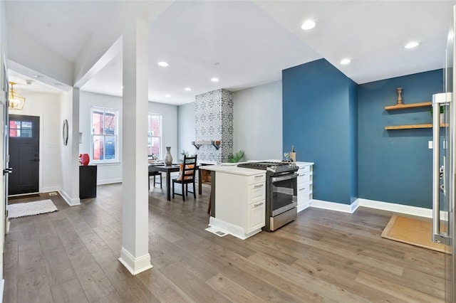 kitchen featuring baseboards, gas stove, light countertops, light wood-style floors, and recessed lighting