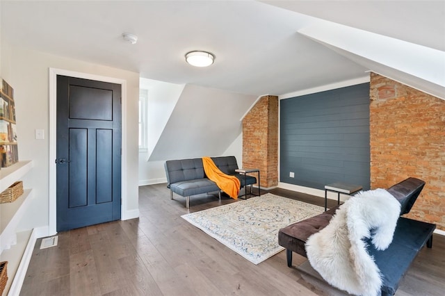 sitting room with baseboards, vaulted ceiling, and wood finished floors