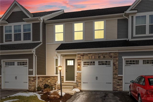 view of property with driveway, stone siding, a garage, and entry steps