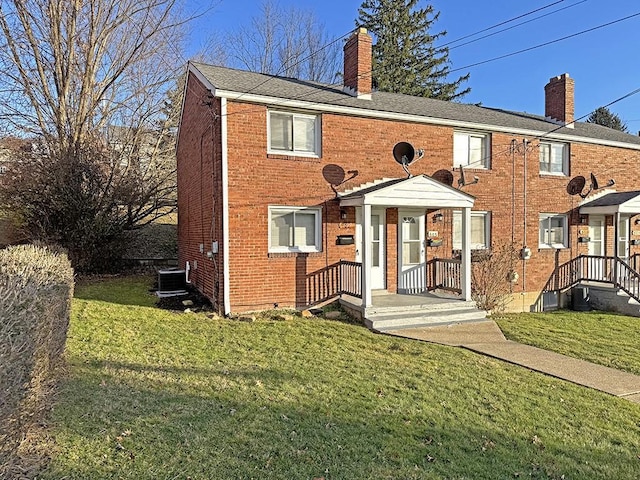 view of front of property featuring central AC, brick siding, a front lawn, and a chimney