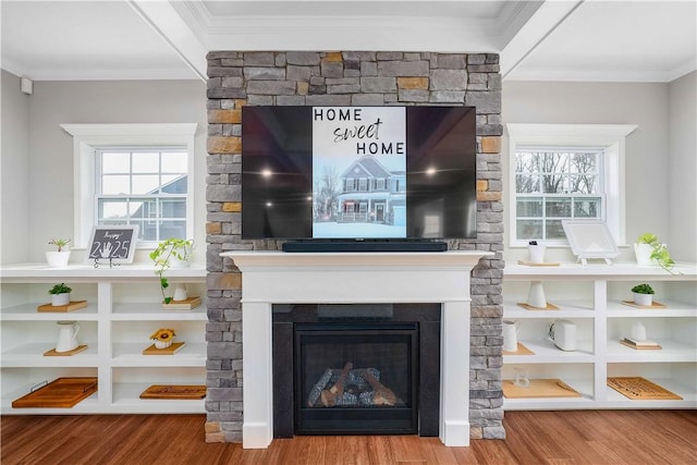 interior details with ornamental molding, a glass covered fireplace, and wood finished floors