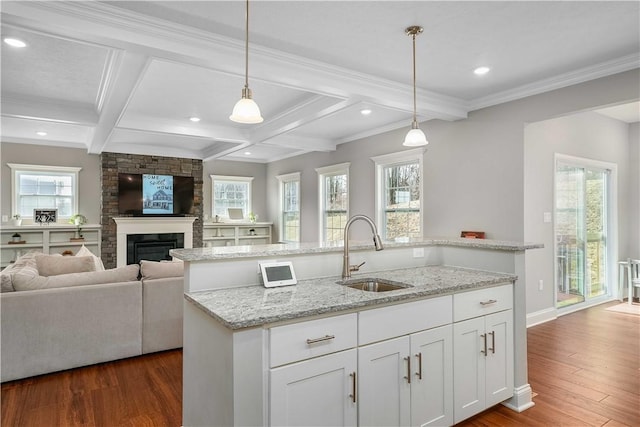 kitchen with hanging light fixtures, white cabinets, open floor plan, and a sink