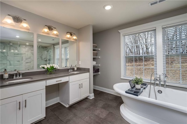 bathroom featuring double vanity, a stall shower, baseboards, a freestanding bath, and a sink