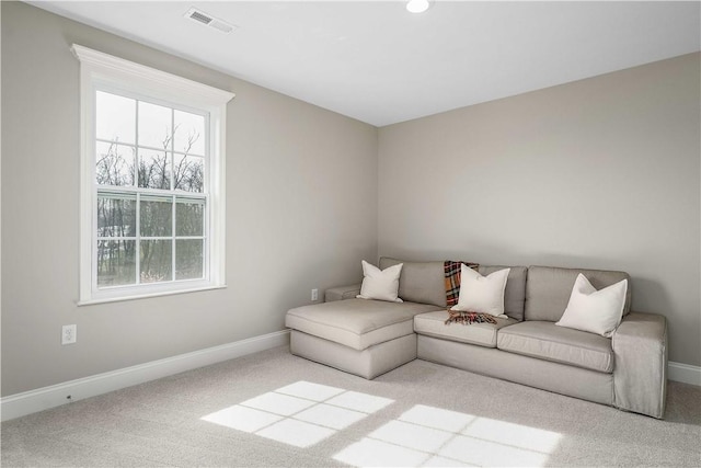 living area featuring visible vents, light carpet, and baseboards