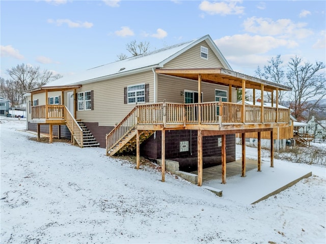 snow covered property featuring stairway and a wooden deck