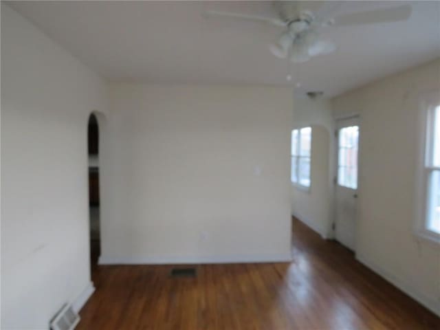 empty room with baseboards, ceiling fan, visible vents, and wood finished floors